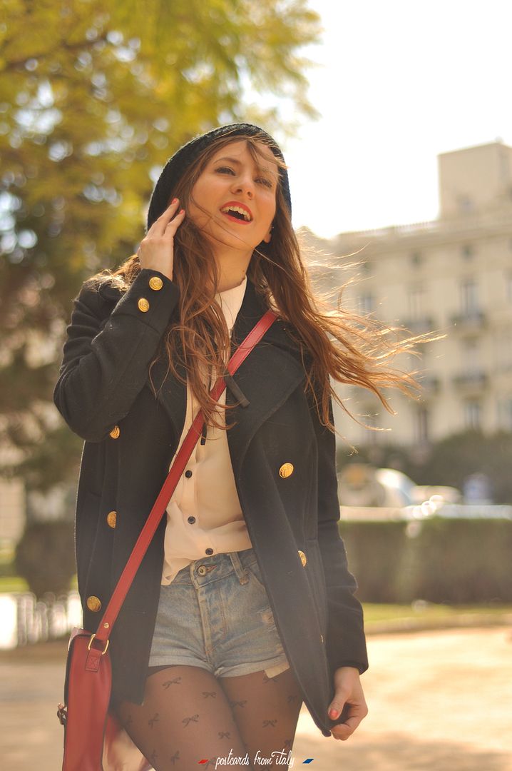 Camisa blanca con lazo negro, short denim y satchel rojo.'