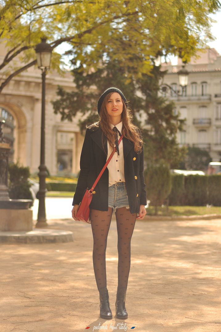 Camisa blanca con lazo negro, short denim y satchel rojo.'