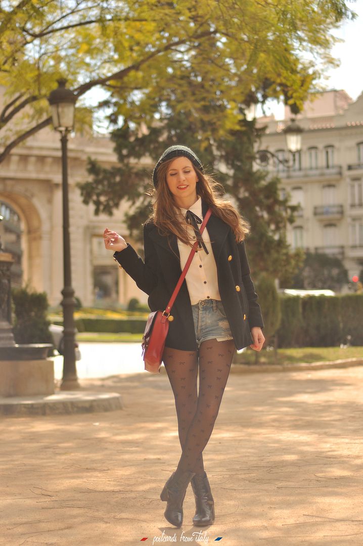 Camisa blanca con lazo negro, short denim y satchel rojo.'