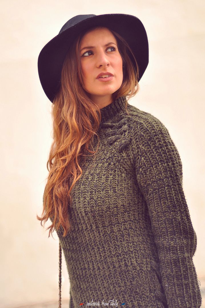 Outfit de jersei trenzado verde, sombrero negro y botines metalizados