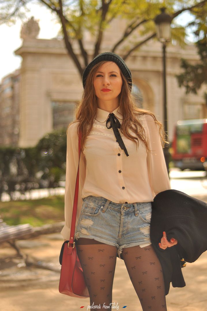 Camisa blanca con lazo negro, short denim y satchel rojo.'