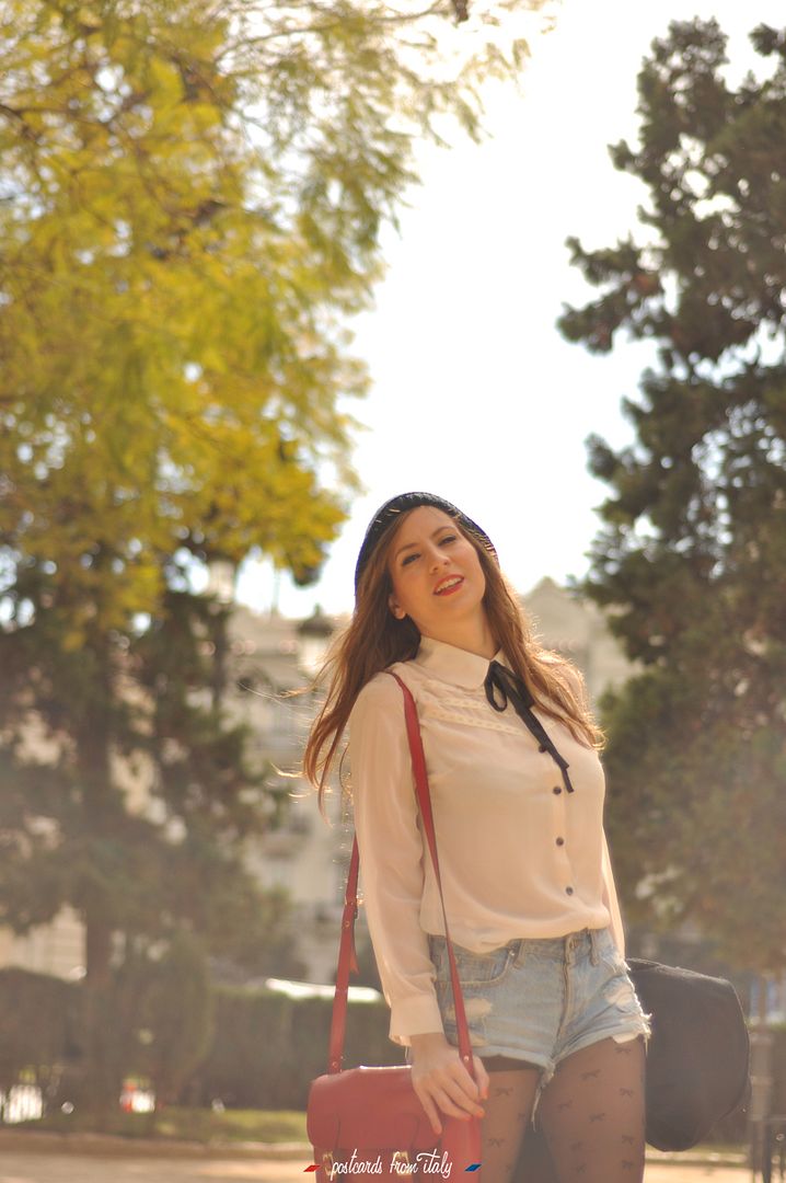 Camisa blanca con lazo negro, short denim y satchel rojo.'